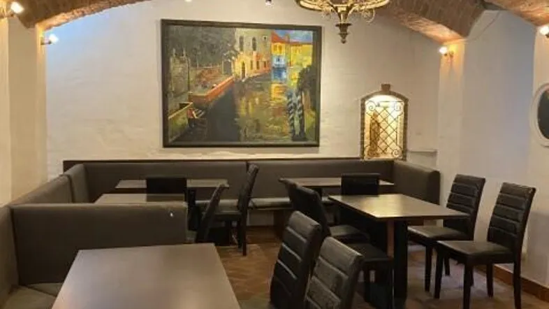 Gemütlicher Restaurantbereich mit Gewölbedecke, Ziegelwänden und traditioneller Beleuchtung, ideal für Gäste.