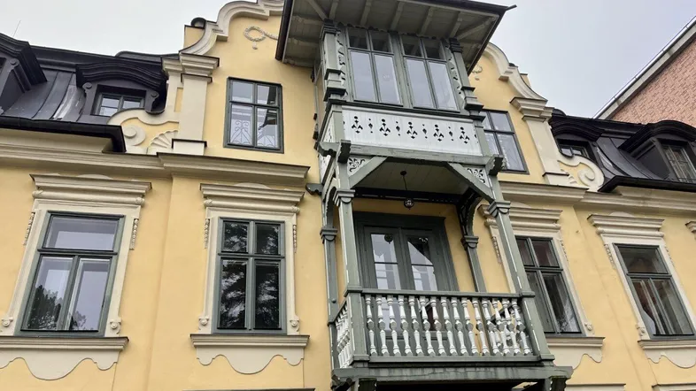 Historische Fassade eines Gebäudes mit aufwendigen Verzierungen und einem charmanten Holzbalkon.