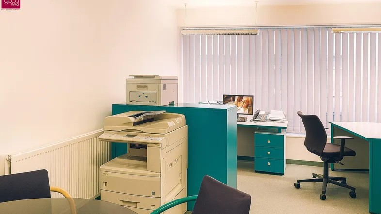 Funktionaler Bürobereich mit Schreibtischen, Bürostühlen und Kopiergeräten, gut beleuchtet.