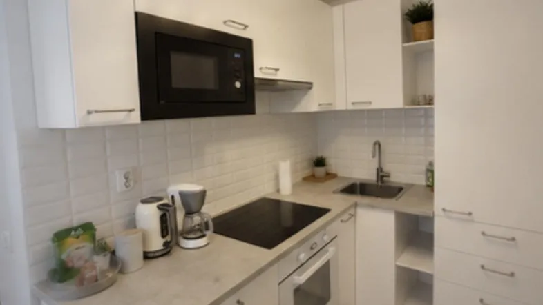 Moderne, helle Küche mit weißen Hochglanzschränken, integrierten Geräten und Fliesenrückwand.