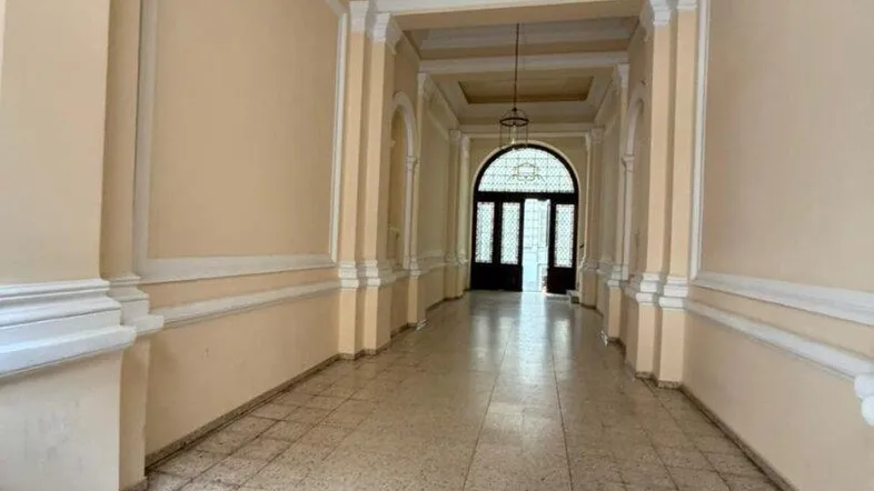 Langer, eleganter Flur mit Stuckdecken, Terrazzoboden und hohen Türen am Ende des Ganges.