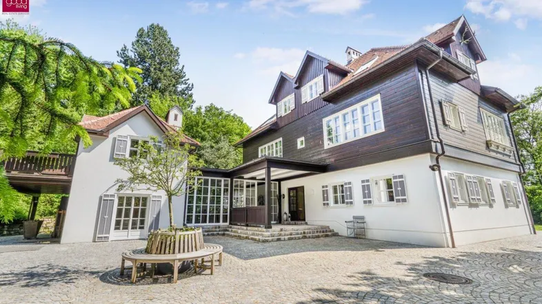 Historisches Anwesen mit gepflastertem Vorplatz und umgebender Natur.