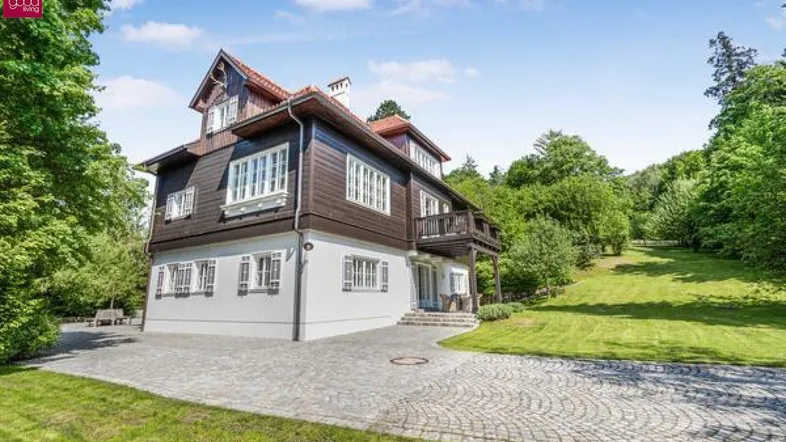 Elegantes Landhaus mit dunkler Holzfassade und weitläufigem grünen Grundstück.
