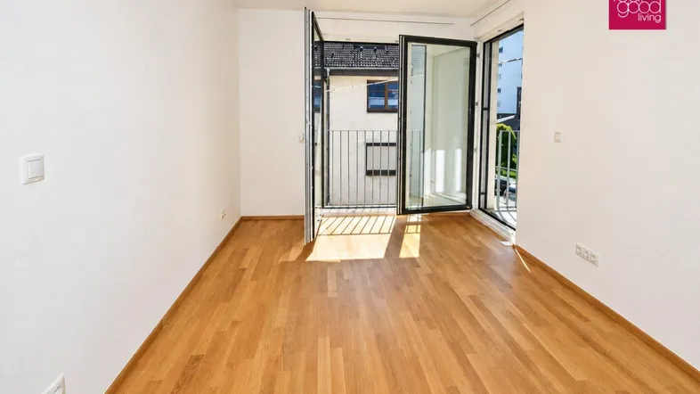Helles Zimmer mit Parkettboden und Zugang zu einem Balkon, ideal als Schlaf- oder Arbeitszimmer.