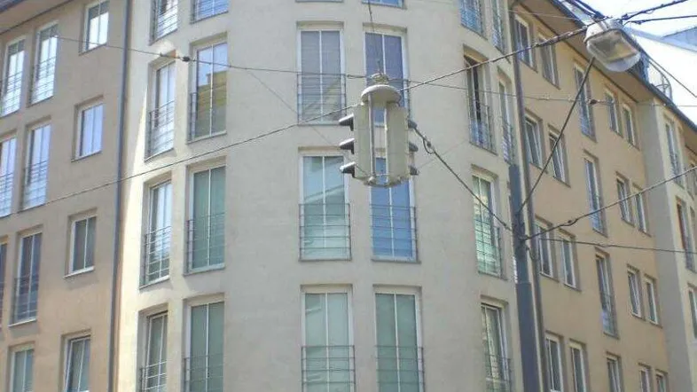 Modernes Eckgebäude mit geschwungener Fassade und großen Fenstern in städtischer Umgebung.