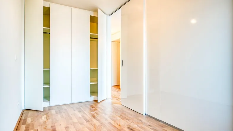 Helles Schlafzimmer mit Einbauschränken und Holzboden in modernem Stil.