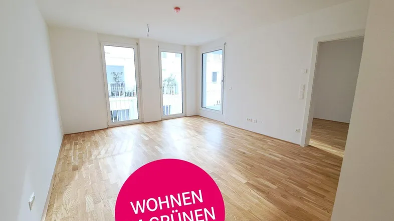 Heller, leerer Wohnraum mit Eichenparkettboden und großen Fenstern, die viel Tageslicht hereinlassen.