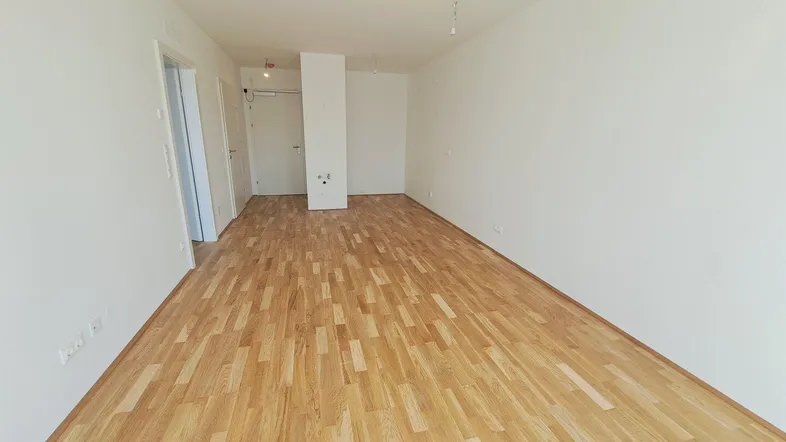 Heller, leerer Wohnraum mit neuem Parkettboden und weißen Wänden, bereit zum Einzug.