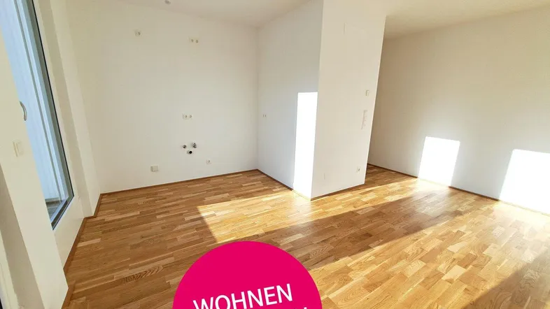 Heller, leerer Wohnraum mit neuem Parkettboden und viel Tageslicht.