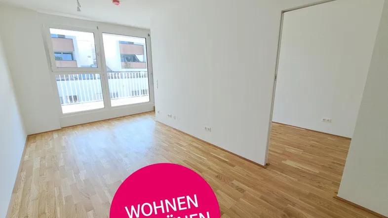 Heller Wohnraum mit Parkettboden und Zugang zu einem Balkon, ideal für modernes Wohnen.