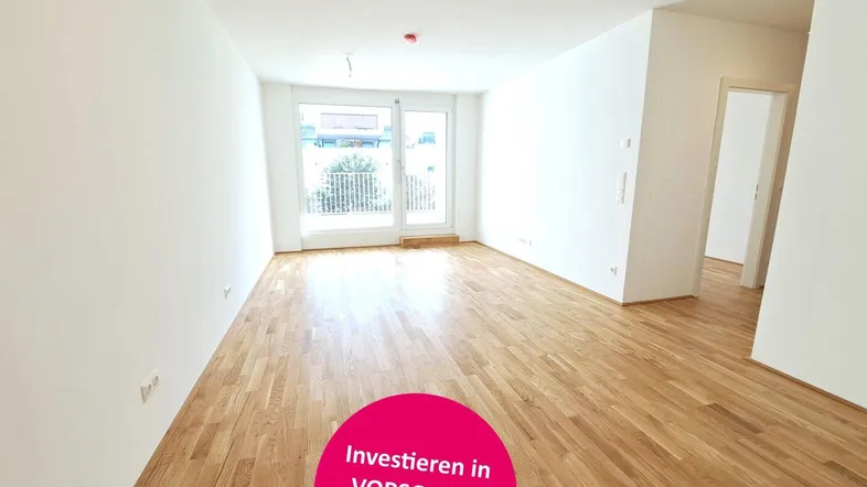 Heller Wohnbereich mit neuem Parkettboden und Zugang zu einem französischen Balkon.