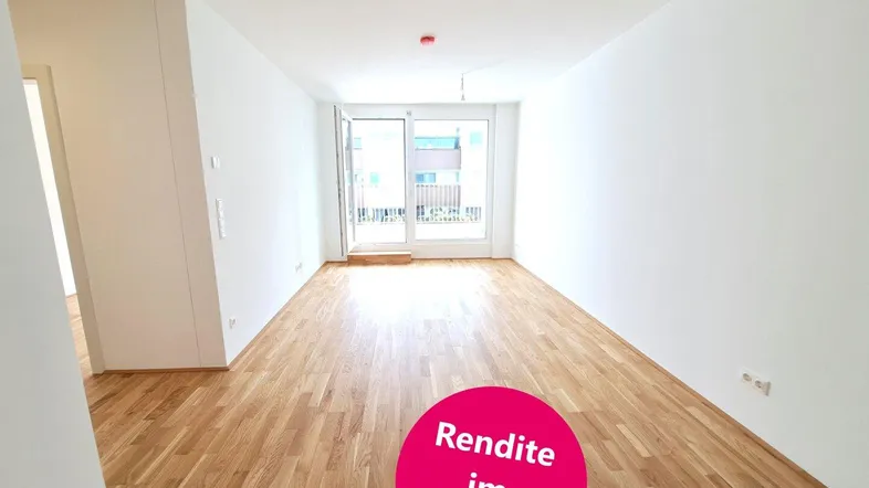 Heller, leerer Raum mit Holzboden und Zugang zu einem Balkon, ideal für Wohnzwecke.