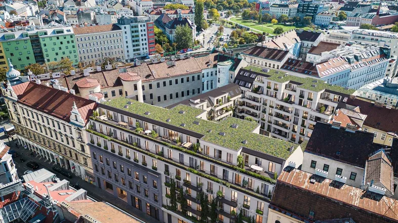 Luftaufnahme eines modernen Wohnkomplexes mit begrüntem Dach und Balkonen in städtischer Umgebung.