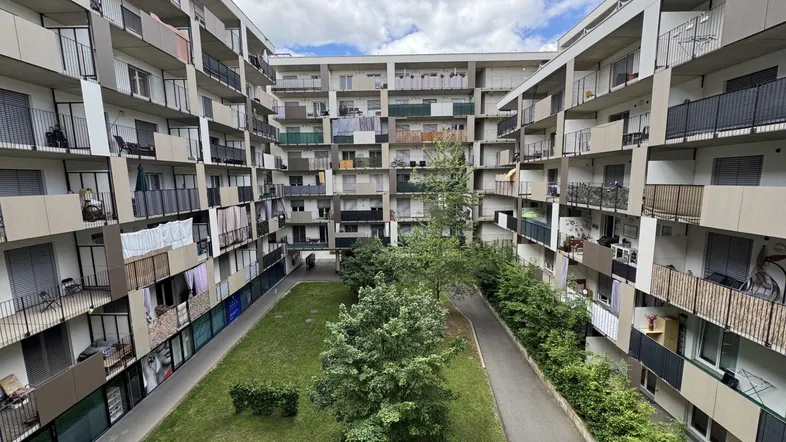 Blick auf den Innenhof eines modernen Wohnkomplexes mit vielen Balkonen und Grünflächen.