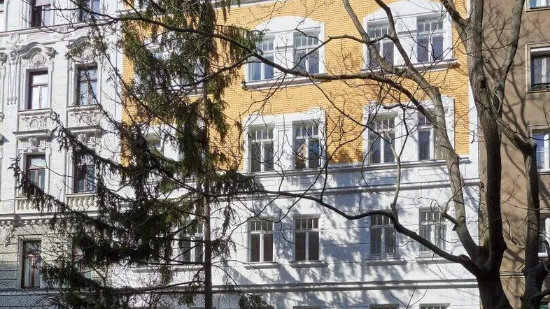 Historisches Mehrfamilienhaus mit klassischer Architektur und gelb-weißer Fassade.