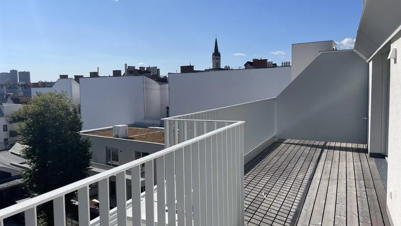 Geräumige Dachterrasse mit Holzboden und weitem Blick über die Stadt, ideal für Entspannung im Freien.