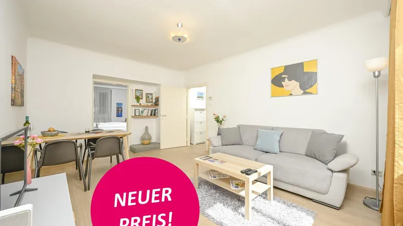 Helles Wohn- und Esszimmer mit Laminatboden, modernem Sofa und Esstisch.