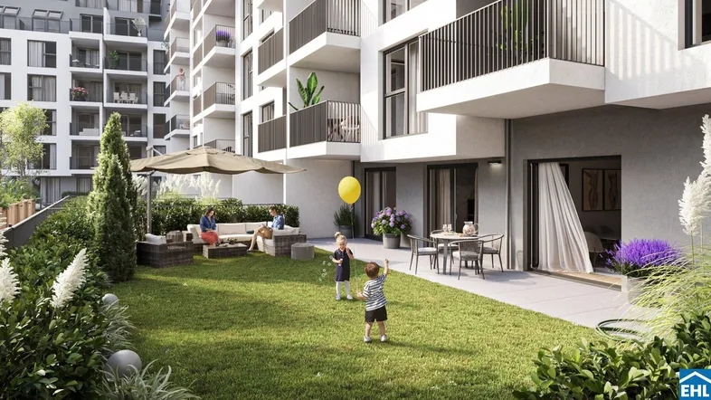 Gepflegter Gemeinschaftsgarten mit Terrasse und Spielbereich vor moderner Wohnanlage.
