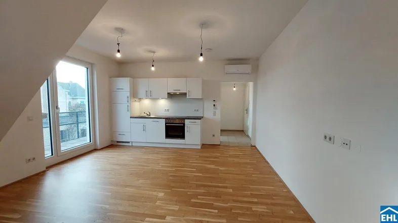 Heller Wohn-Essbereich mit integrierter weißer Küche, Parkettboden und Zugang zu einem Balkon.