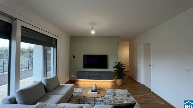 Modernes Wohnzimmer mit bequemer Couch, Holzboden und Zugang zur Terrasse.