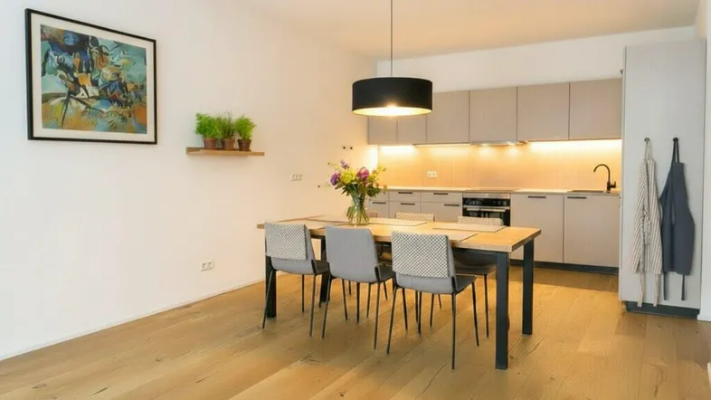 Heller offener Wohnbereich mit Esstisch und integrierter moderner Küche mit Holzboden.