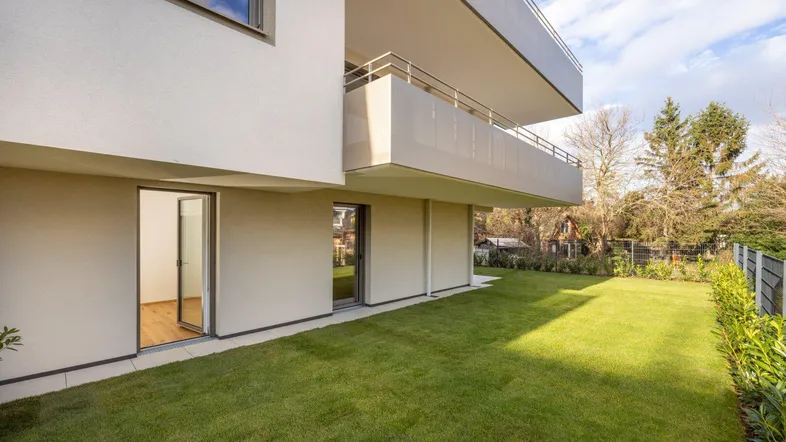 Moderne Wohnanlage mit gepflegtem Rasen und direktem Zugang zum Gartenbereich.
