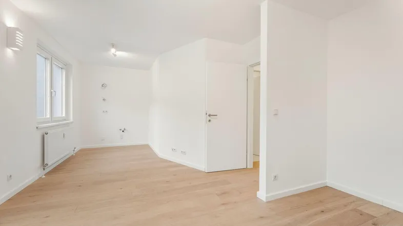 Heller Raum mit neuem Parkettboden, weißen Wänden und großem Fenster, bereit zur Einrichtung.
