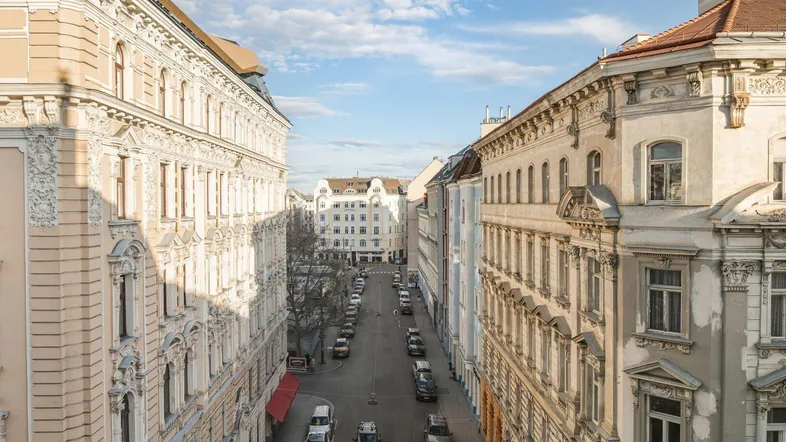 Blick von oben auf eine belebte Straße mit historischen Gebäuden und parkenden Autos.