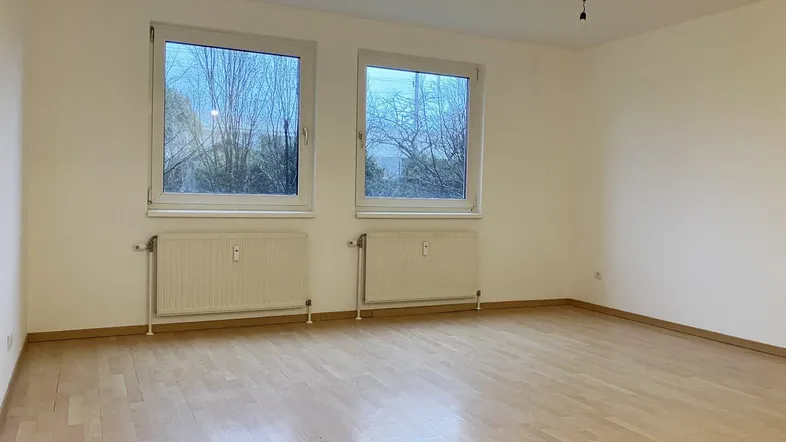 Helles Zimmer mit Parkettboden und zwei Fenstern, ideal als Wohn- oder Schlafzimmer, in gutem Zustand.
