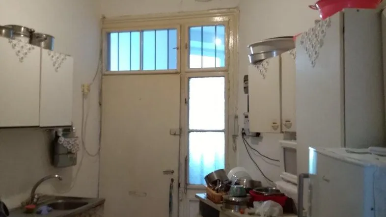 Einfache Küche mit älteren Geräten, Holzfußboden und Fenster zum Hof.