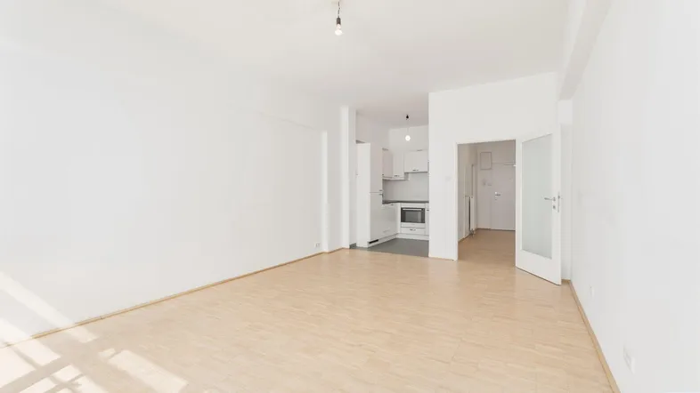 Helles Wohnzimmer mit Parkettboden und integrierter Küchenzeile, ideal für Singles oder Paare.