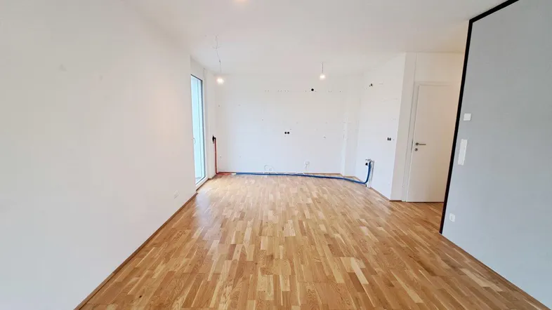 Geräumiger, heller Raum mit Parkettboden und Zugang zum Garten, ideal für Wohn- oder Essbereich.