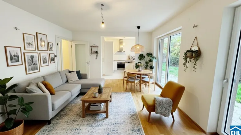 Helles, offenes Wohn-Esszimmer mit gemütlicher Sitzecke, Esstisch und Blick in die Küche.
