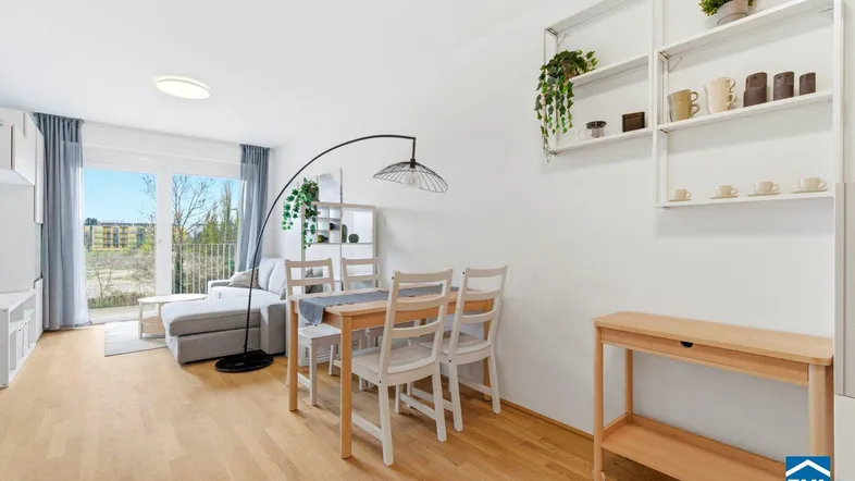 Heller Wohn- und Essbereich mit Holzboden, modernem Esstisch und Zugang zum Balkon.