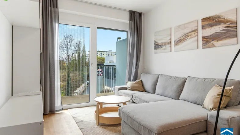 Helles Wohnzimmer mit modernem Sofa, Holzboden und Zugang zu einem Balkon.