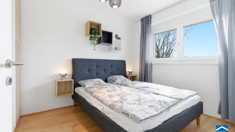 Helles Schlafzimmer mit Holzboden, modernem Bett und dekorativen Wandregalen.