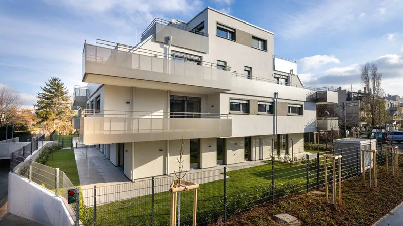 Modernes Mehrfamilienhaus mit klaren Linien, großzügigen Balkonen und gepflegten Grünflächen.