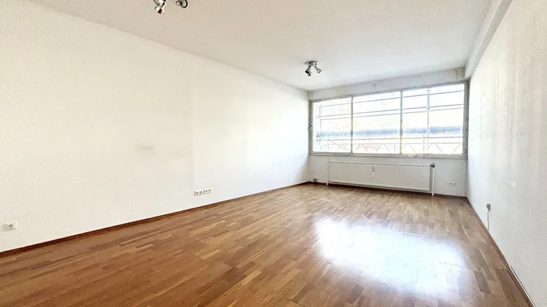 Helles, leeres Zimmer mit Parkettboden und großen Fenstern, bereit zur individuellen Gestaltung.