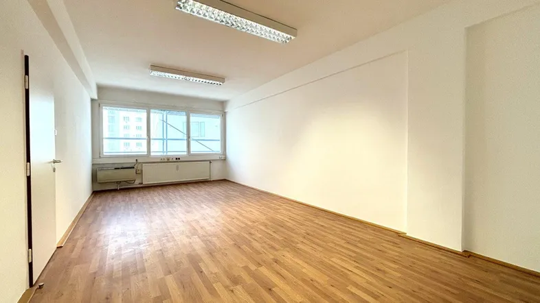 Leerer Raum mit Holzboden und großen Fenstern, ideal für verschiedene Nutzungen.