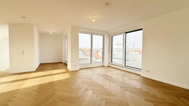 Helles und geräumiges Wohnzimmer mit elegantem Fischgrätparkett und großen Fenstern für viel Tageslicht.