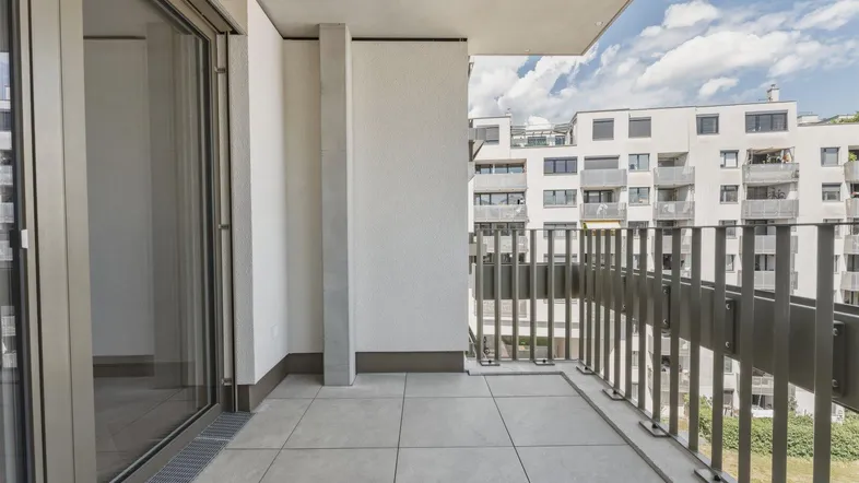 Geräumiger Balkon mit Fliesenboden und Blick auf die umliegenden Gebäude.