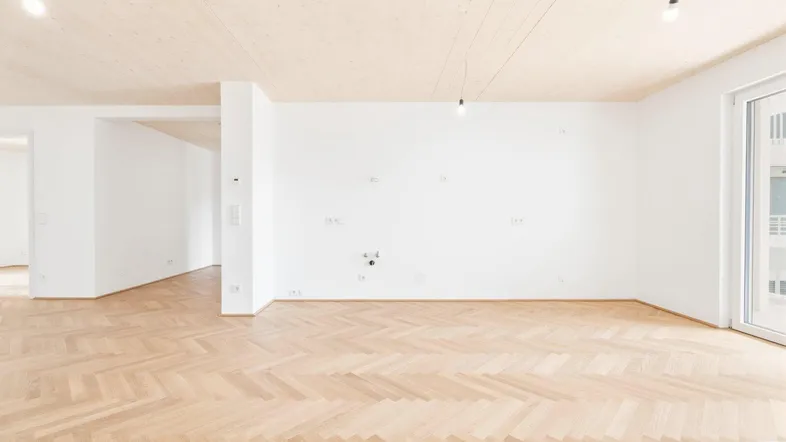 Helles, leeres Zimmer mit Fischgrätparkett und Holzdecke, bereit für die individuelle Gestaltung.