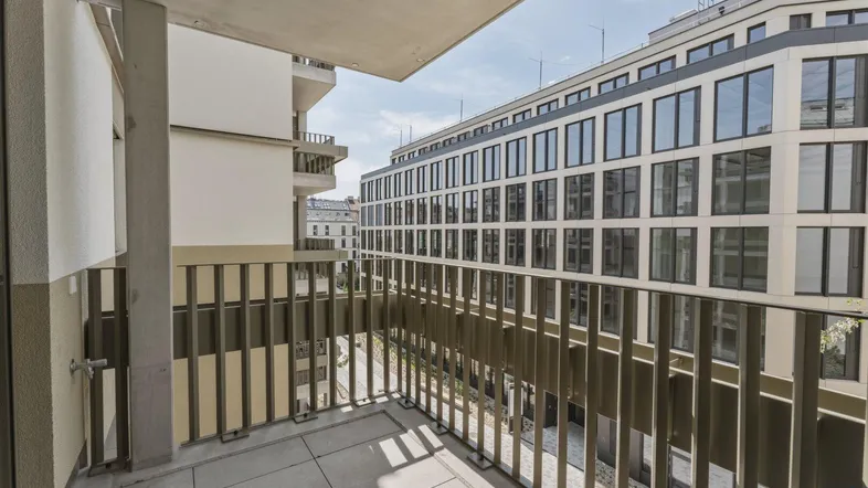 Geräumiger Balkon mit Fliesenboden und Blick auf die umliegenden modernen Gebäude.