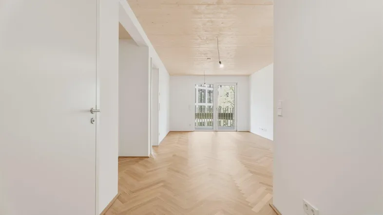 Heller, leerer Raum mit Fischgrätparkett und Holzdecke, bereit zur individuellen Gestaltung.