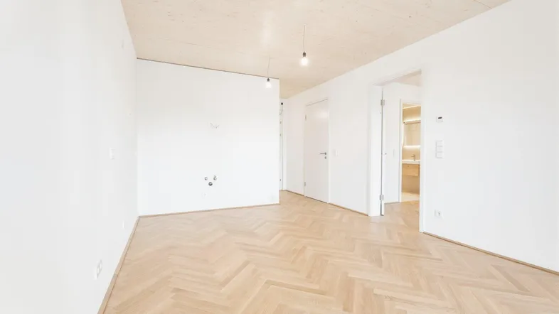 Helles, leeres Zimmer mit Fischgrätparkett und Holzbalkendecke, bereit zur individuellen Gestaltung.
