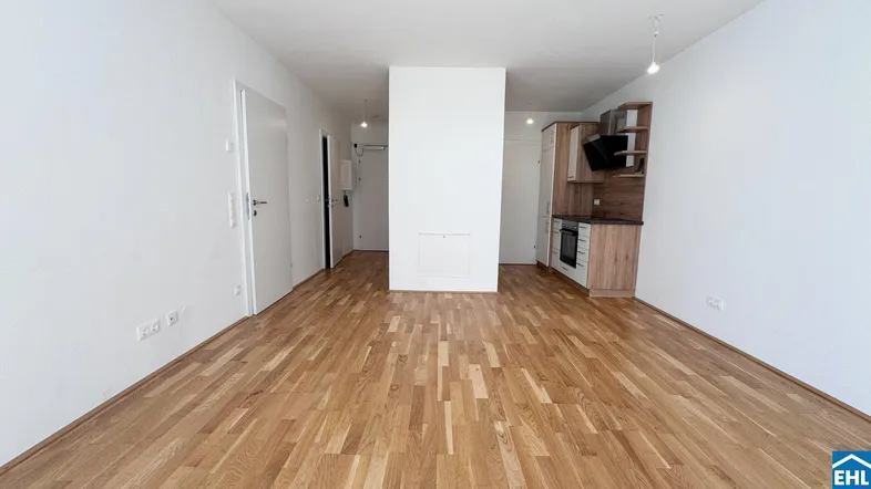 Helles Wohnzimmer mit Parkettboden und integrierter Küchenzeile in modernem Design.