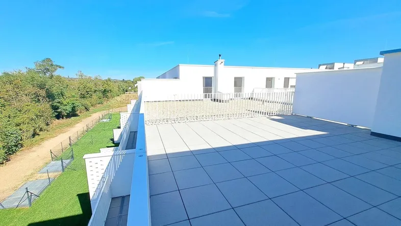 Große Dachterrasse mit modernen Fliesen, weißen Geländern und weitem Blick ins Grüne.