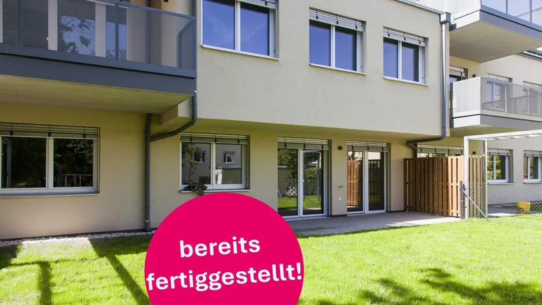 Neubau-Fassade mit Balkonen und direktem Zugang zu privaten Gartenflächen im Erdgeschoss.