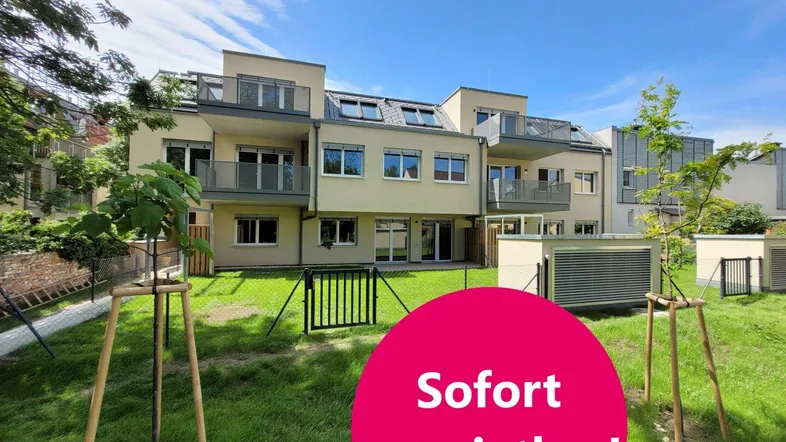 Modernes Mehrfamilienhaus mit Balkonen und einer grünen Rasenfläche im Vordergrund.