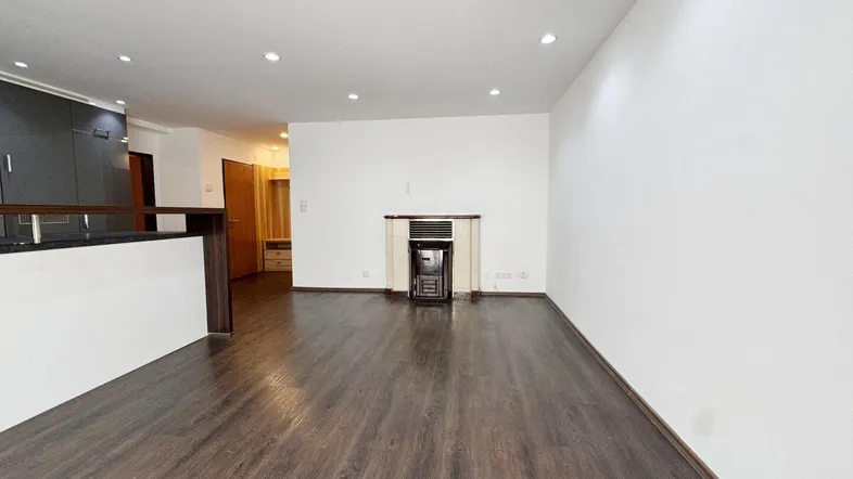 Geräumiges Wohnzimmer mit dunklem Laminatboden, Einbaustrahlern und einem dekorativen Kamin.